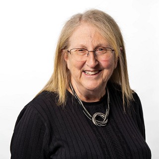 Headshot for Nancy Kirsch, wearing a black shirt and glasses.