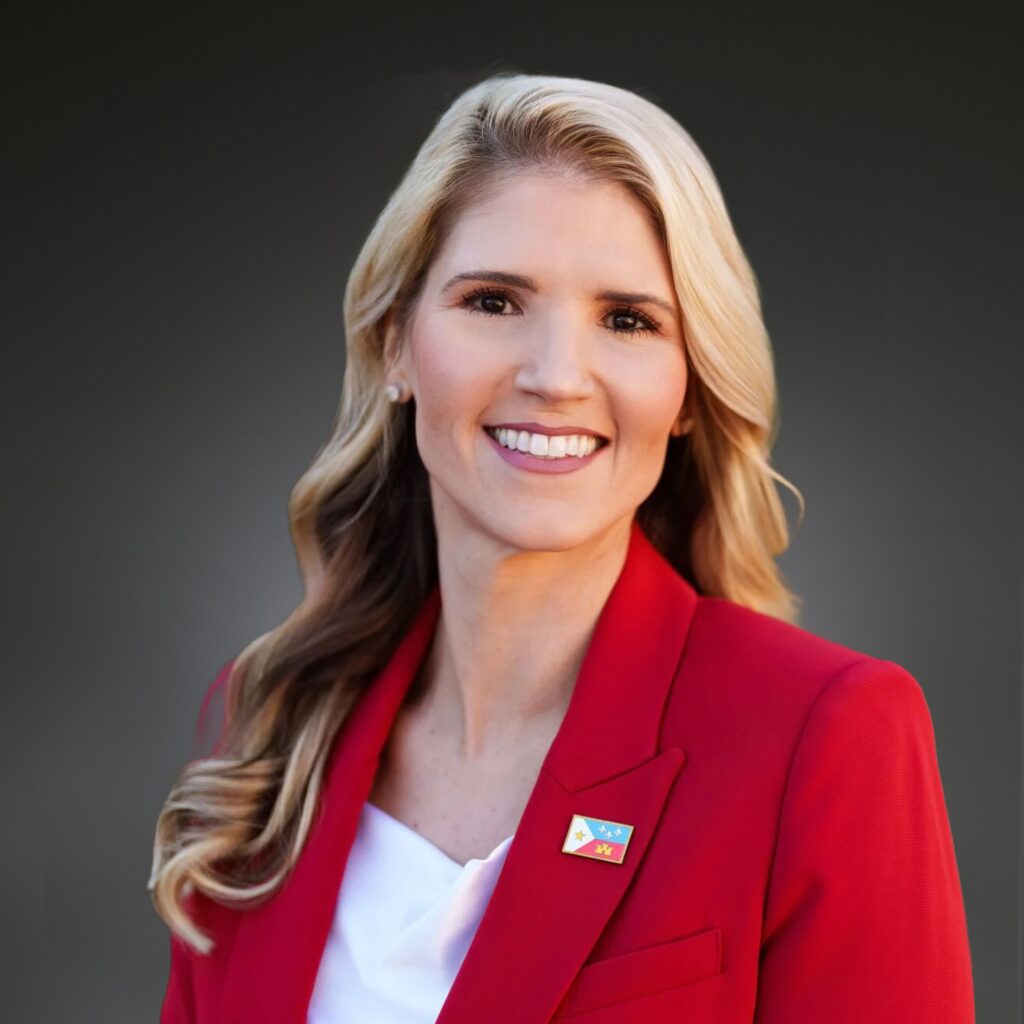 Headshot for Annie Spell wearing a red blazer over a white blouse.